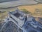 Aerial shot of an ancient ruined castle in the middle of crop fields