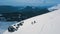 Aerial shot backpacker wearing snowboard and ski equipment climbing on top of high mountain