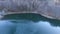 Aerial shot, a beautiful frozen lake in deep blue color, surrounded by frost trees, situated in the middle of the mountains