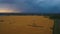 Aerial shot of beautiful massive wheat field with rain and lightnings going on on the background