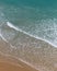 Aerial shot of the beautiful ocean waves meeting the sand on the beach