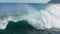 Aerial shot of breaking surf with foam in Pacific Ocean. Drone Slow motion barreling wave with texture and wind spray