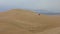 Aerial shot of buggy jeep driving in huge sand Peruvian dunes, side shot.