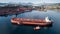 Aerial shot of a cargo ship approaching port terminal with help of towing ship