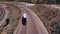 Aerial shot of cars and white truck driving by camera on beautiful highway road in the middle of sandstone rocky desert.