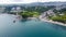 Aerial shot of the coastal city between the green lands and trees