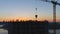 Aerial shot of construction site with cranes and workers at sunset