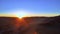 Aerial shot from drone of setting sun over wide african desert. Flare of light and colourful sky at dusk. Amazing relief