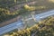 Aerial shot of an ecoduct highway with traffic in the middle of a green forest