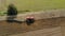Aerial shot of a farmer on a red tractor processing farmland with a reverse plow with support wheels