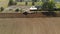 Aerial shot of a farmer on a red tractor processing farmland with a reverse plow with support wheels