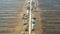 Aerial shot flying along road over peat harvesting field. Peat extraction. Piles of peat