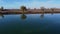 Aerial shot flying away from a levee with trees and reflections in water