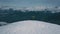 Aerial shot flying over winner male snowboarder admiring mountain landscape from peak of rock