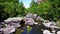 Aerial shot following close behind a group of kayakers paddling down whitewater rapids in the water of deep blue river