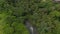 Aerial shot following the flow of a jungle river hidden by a thick lush vegetation in a tropical rainforest