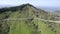 Aerial shot of forested mountains with long roads and green fields