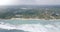 Aerial shot of happy family sitting near a house on exotic shore, revealing epic huge ocean panorama with crashing waves