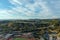 Aerial shot of hillside covered with lush green trees in front of Dodgers Stadium surrounded by buildings, cars, streets