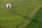 Aerial shot of a hot air balloon landing in a green grass field with landing spot marked by X