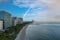 aerial shot of hotels, luxury condos and skyscrapers along the coastline at sunrise at Bal Harbour Beach, blue ocean water