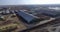 aerial shot of huge solar powered farm in rural landscape, livestock buildings and bales of hay