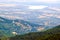 Aerial shot of a land surrounded by mountains covered in greens