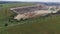 Aerial shot of landfill with working excavator moving garbage.