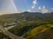 An aerial shot of the majestic mountain ranges with homes along the coastline of California, freeways with cars and powerful cloud