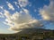 Aerial shot of majestic mountains with powerful clouds and blue sky with homes, apartments and lush green trees in Monrovia