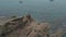 Aerial shot of a man standing on a cliff above a clear transparent sea