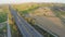 Aerial shot of many trees, harvested farming fields, green hills along highway