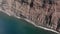 Aerial Shot. Ocean coast, cliff on the seashore. Blue water and red rock. Diagonal plan. Canary Islands, Tenerife, Los