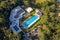 Aerial shot of an outdoor olympic size, six lane, swimming pool at an exercise gym complex surrounded by trees and park in