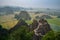 Aerial shot of rocky cliffs in a green landscape enveloped with fog