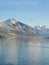 Aerial shot of a sailboat drifting across the lake, with snow-capped mountains in the background