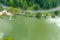 An aerial shot of the silky green waters of the lake surrounded buy lush green trees and a smooth footpath circling the water