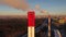 Aerial shot of the skyline of Moscow behind red and white industrial smoke stacks in winter evening, Russia