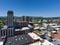 aerial shot of skyscrapers, office buildings, and apartments with lush green trees, mountains, cars on the street