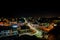 Aerial shot of a small night city and a long exposure on the road where cars rush fast