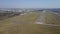Aerial shot of a small propeller airplane flying near city airport runway on a sunny day. 4K video