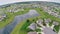 Aerial shot of a suburban neighborhood with curving roads and cul de sac and a pond and green lawns