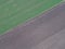 Aerial shot of a textured gray road near flat grass