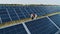 Aerial shot of three solar energy engineers on a large solar farm. Three employees of alternative power plant walking