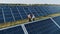 Aerial shot of three solar energy engineers on a large solar farm. Three employees of alternative power plant walking