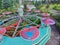 Aerial shot of a tilt a whirl at an abandoned theme park surrounded by trees and grasses