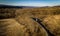 Aerial shot of a train passing by a picturesque field surrounded by majestic mountains.