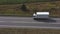 Aerial shot of truck with cargo trailer driving on empty straight road. Flying over white lorry moving along highway