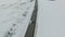 Aerial shot of vehicle and bus driving winter road in snowy field.