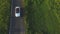 Aerial shot of white convertible car riding through empty rural road. Four young unrecognizable women travelling at